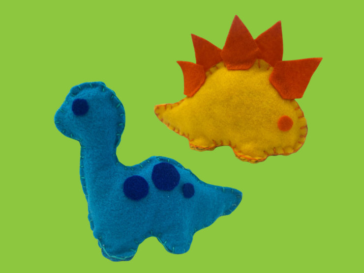 a green background, with two hand sewn felt plush dinosaurs, one a blue brachiosaurus and the other a yellow and orange stegosaurus