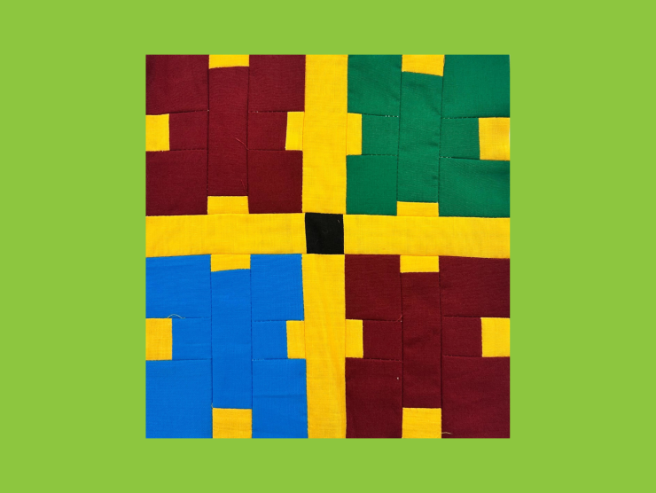 A green background with a quilt block in front. The block is in four sections, two red, one green and one blue. The sections are seperated by yellow. each section is made of small squares and rectangles making blocky x's.